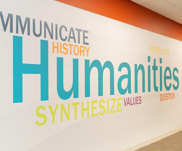 Photo with images of words on a wall, one of which reads "Humanities"