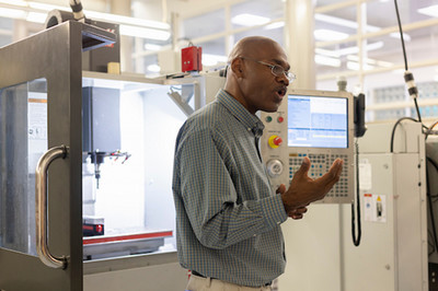 Instructor in front of a CNC machine speaking to a group of students
