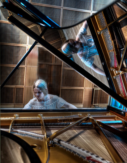 Larry Osher's "Musical Reflections," a young woman plays the piano, her reflection shown at 90 degrees along the piano's open hood.
