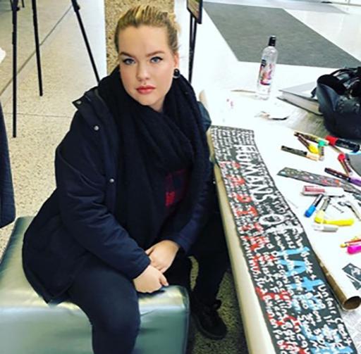 Student sitting near table with sign near her.