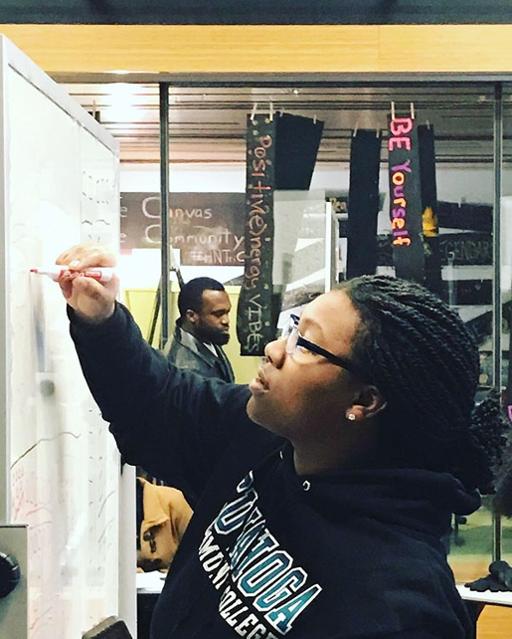 Female student writing on dry-erase board