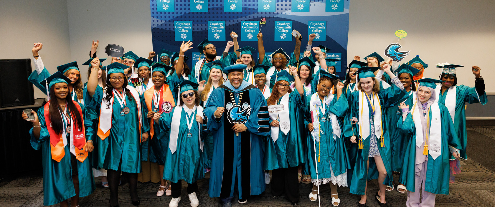 A group of happy grads surrounding Dr. Baston at Commencement