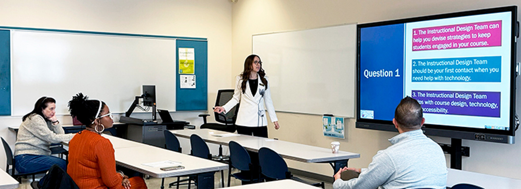 A second view of an Instructional designer in front of a classroom presenting a series of workshops to faculty.
