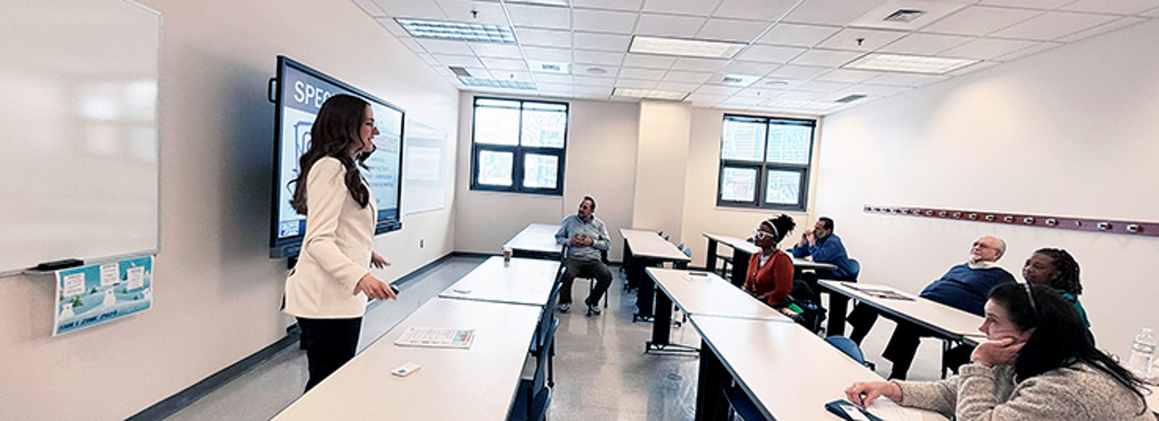 A third view of an Instructional designer in front of a classroom presenting a series of workshops to faculty.