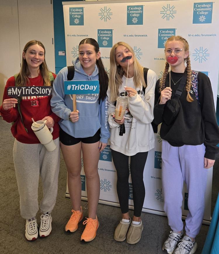 Female students, smiling with selfie props, wearing sweatshirts