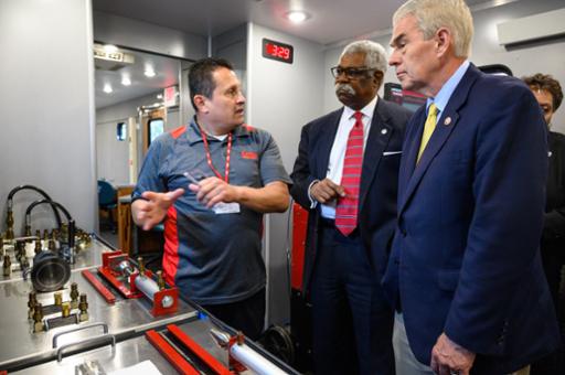 Ohio Department of Higher Education Chancellor Randy Gardner (right) listens with Tri-C's William Gary as an Oatey employee describes the training he has received in the College's mobile training unit.