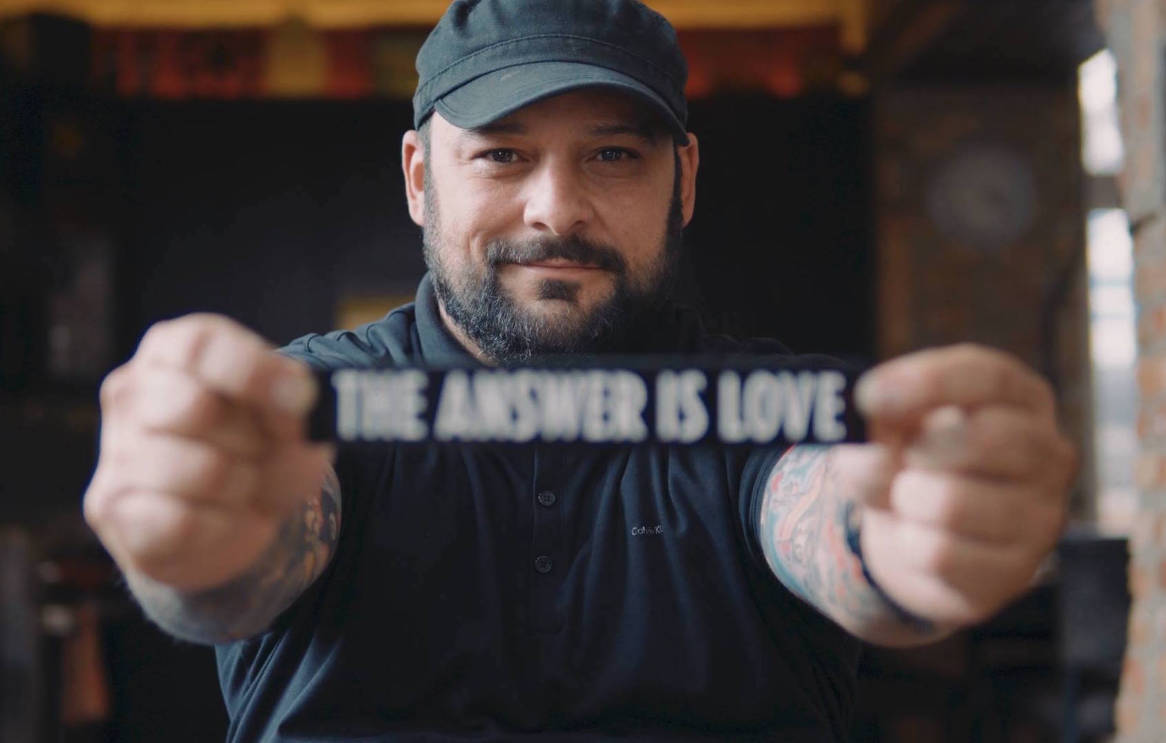 Christian Piccolini holding a sign that says 'The Answer is Love'