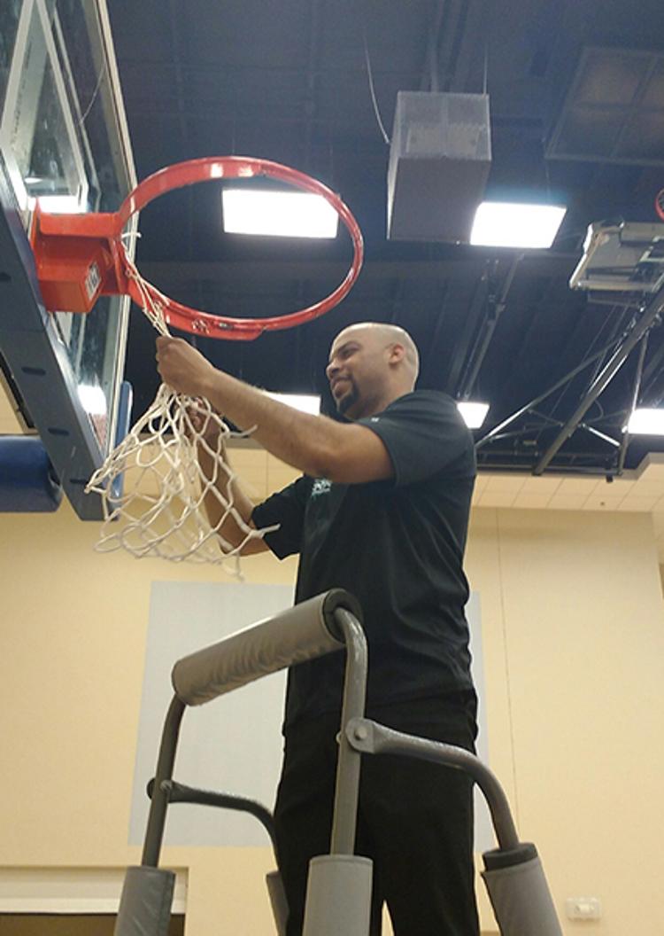 Tri-C men's basketball head coach Michael Duncan cuts down the net after the Challengers won the NJCAA Region XII title on Saturday.