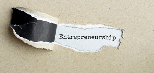 The word "Entrepreneurship" revealed behind ripped paper