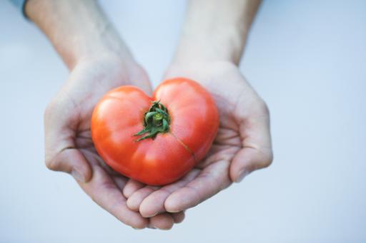 Hands holding heart-shaped tomato