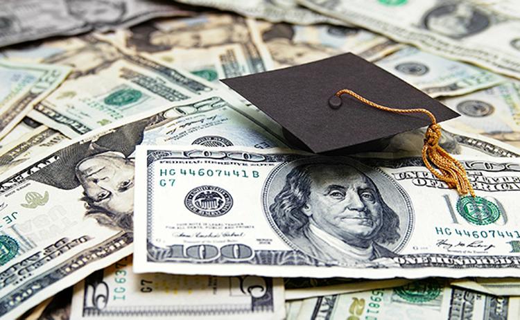 Miniature graduation cap sitting on paper money