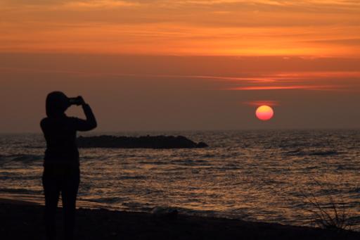 Person taking a picture of a Lake Erie sunset