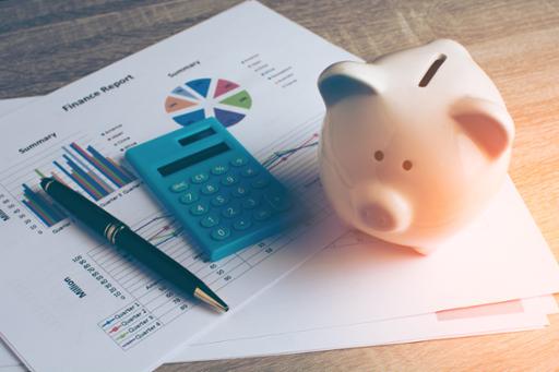 Piggy bank, calculator and pen on a piece of paper with financial information