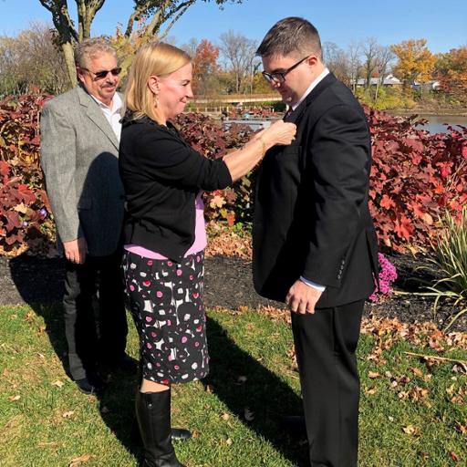 New Berea firefighter Ryan Casey (right) watched as his mother, Kitty Romance, pins the firefighter badge to his suit during his swearing-in ceremony. His stepfather, Tim Romance, is to the left.