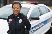 Picture of female, African-American police academy cadet in front of car