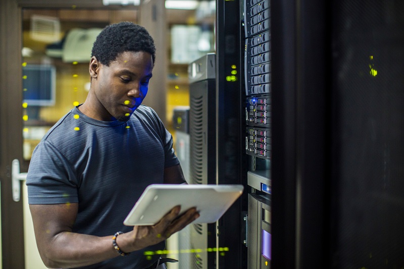 Man standing in front of servers holding tablet