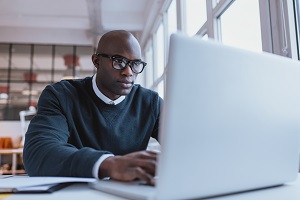 Black man sitting in front of laptop